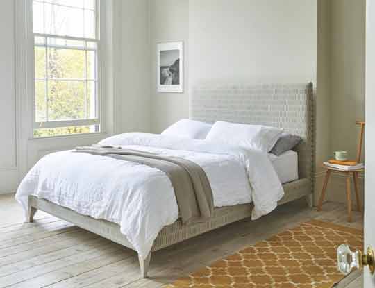 bed in neutral fabric in bedroom